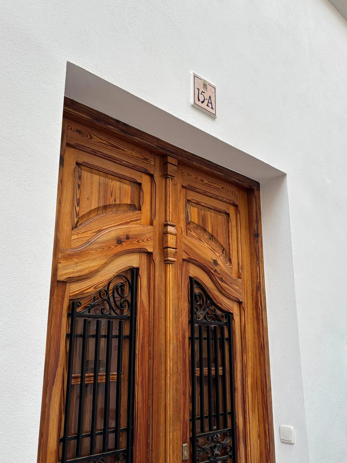 puerta de madera tallada con reja de forja