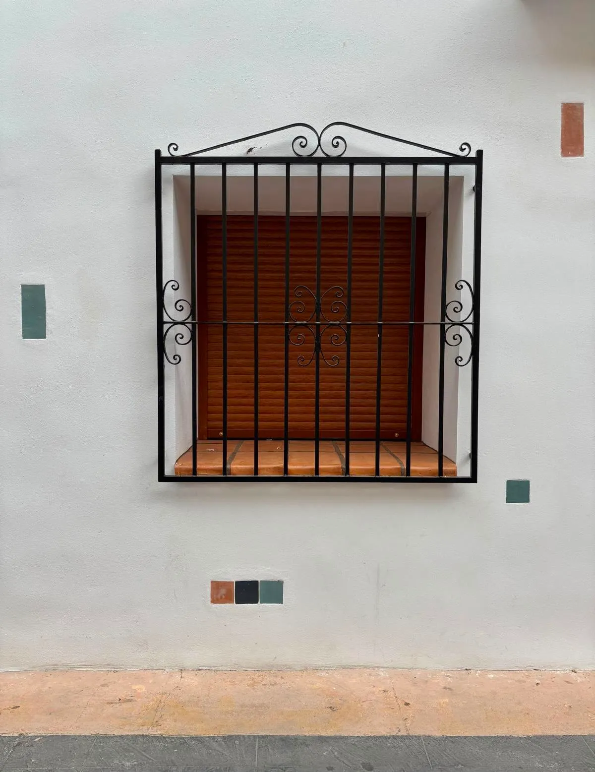 ventana con reja de forja y persiana de madera
