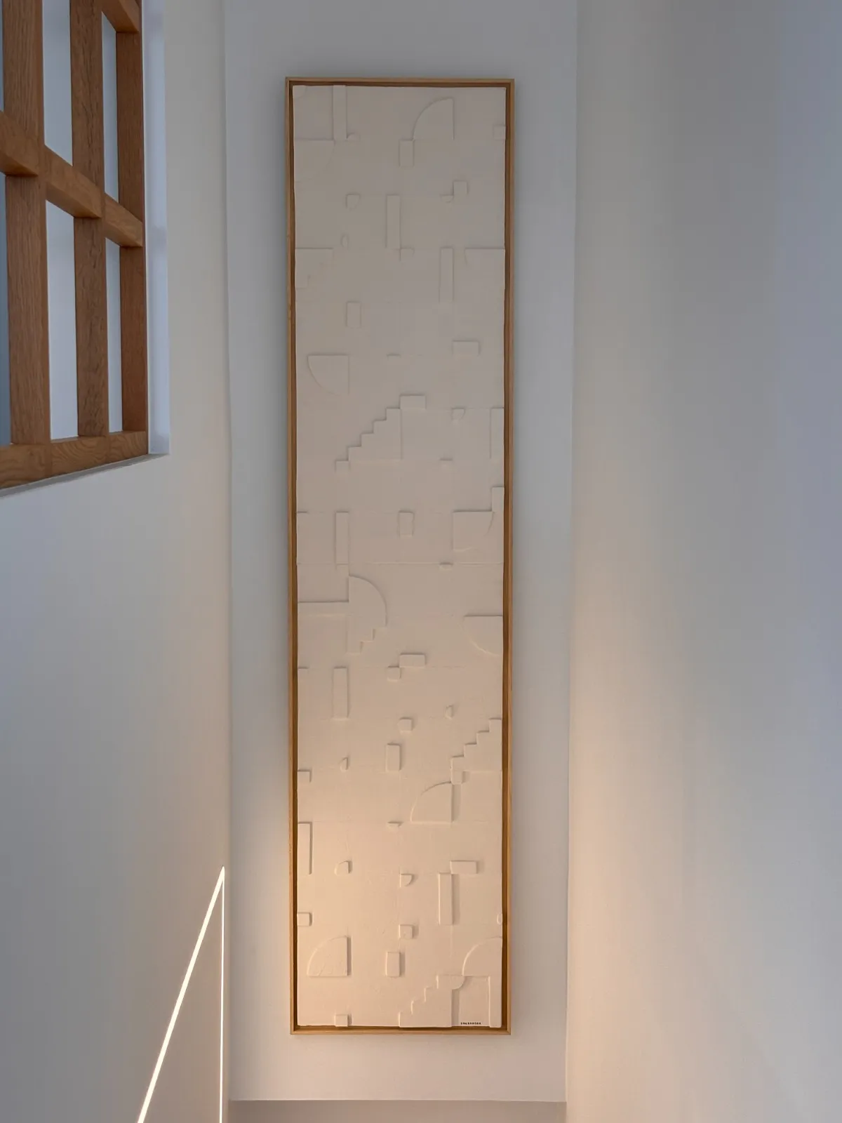 pieza de relieve blanco enmarcada en roble, en el hueco de escalera de UNIC